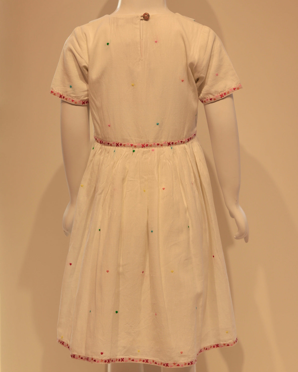 White dress with red trim on a mannequin against a plain background